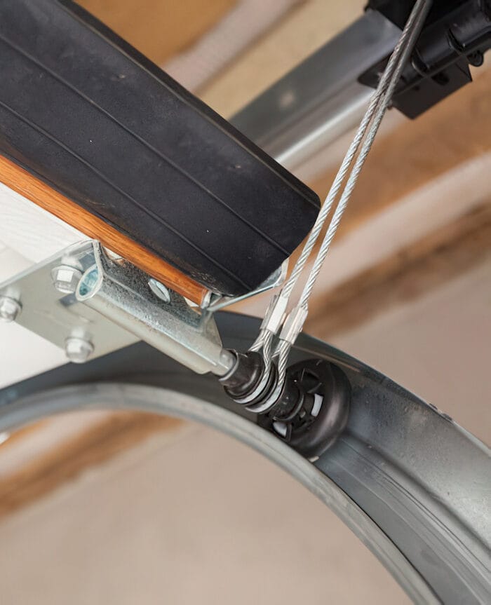 Close-up of garage door steel cables, roller, and track hardware