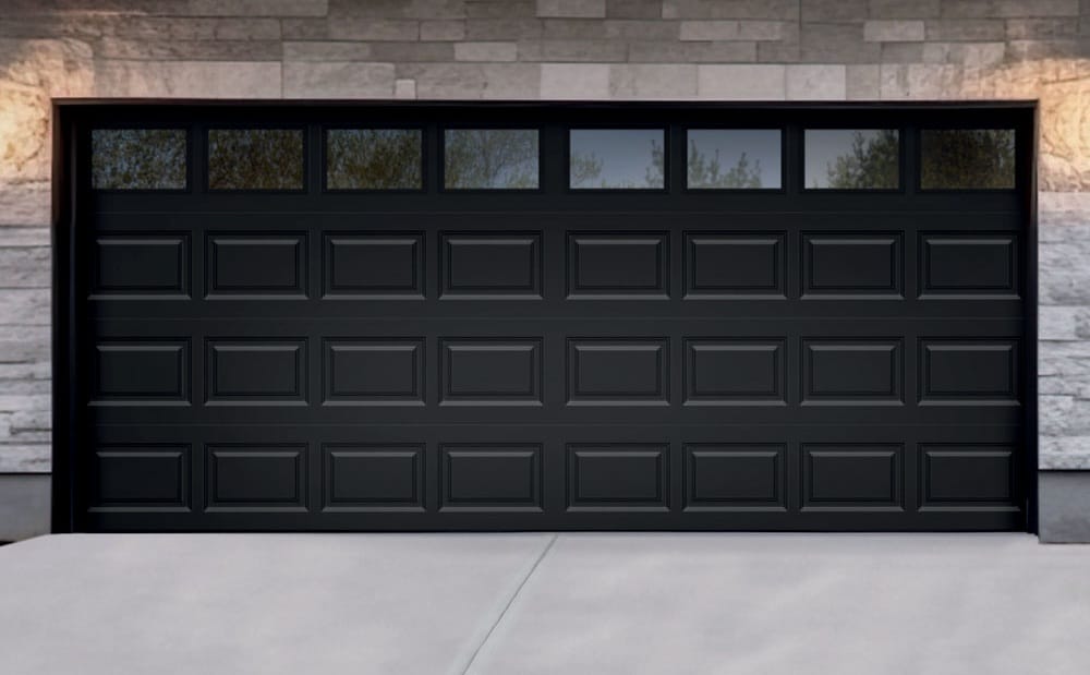 Modern black residential garage door on a stone-clad home